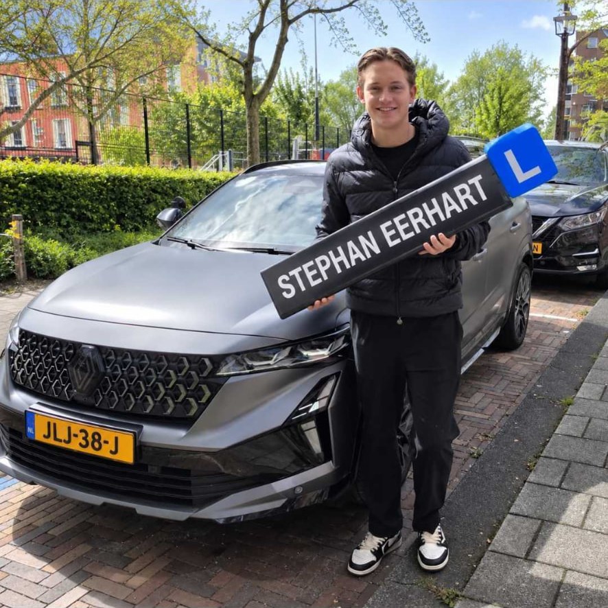 Geslaagde leerling met het bord van Autorijschool Stephan Eerhart